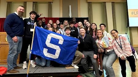 students hold an "S" flag